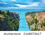 Scenic landscape of the Corinth Canal in a bright sunny day against a blue sky with dramatic clouds. A pleasure boat floats among the rocks in turquoise water. Greece