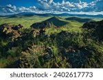 A scenic landscape featuring green hills and a blue cloudy sky. Colton Crater, Arizona