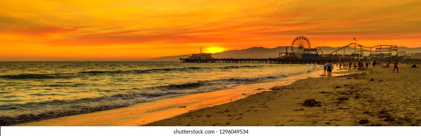 Scenic Landscape Of Iconic Santa Monica Pier At Orange Sunset Sky From The Beach On Paficif Ocean. Santa Monica Historic Landmark, California, USA. Wide Banner Panorama.