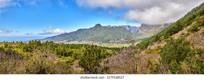 Scenic landscape of mountains in La Palma, Canary Islands, Spain against a cloudy blue sky background with copyspace. Wild plants and shrubs growing on a rocky hill and cliff in natural environment