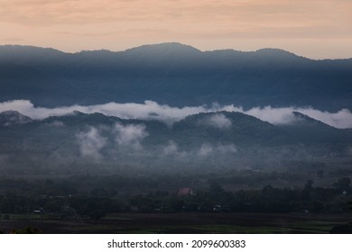 Scenic Landscape of Mountains with Low Lying Fog Over the Hills and Mountains of Lampang Province in Thailand from the Wat Doi Prachan Mae Tha View Point Temple. Beautiful scenery with morning mist.