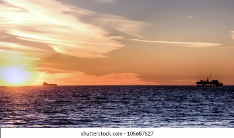 Scenic Landscape Off Shore Oil Rig And Cargo Ship At Sunset