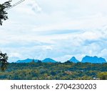 A scenic landscape in West Java, Indonesia, featuring lush green hills and mountains under a bright, cloudy sky. A serene view of nature