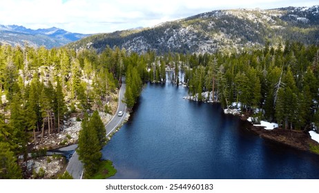 Scenic Mountain Lake with Forest Road. Aerial view of a serene mountain lake surrounded by dense pine forests and winding roads, showcasing stunning natural scenery. - Powered by Shutterstock