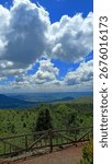 Scenic mountain landscape with dramatic clouds and lush green forest view under bright blue sky in Indonesia