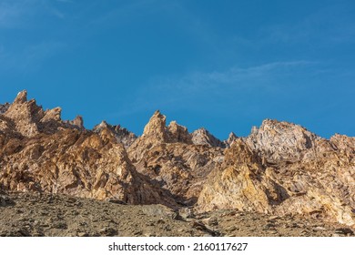 Scenic mountain landscape with sharp rocks under blue sky in sunny day. Colorful scenery with gold sunlit sharp rocky mountains. Sharp rocks in bright sun. High rocky mountains in golden sunlight.