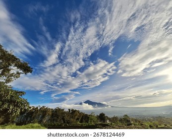 A scenic mountain view with dramatic cloud formations and clear blue sky, surrounded by natural greenery and fresh atmosphere.