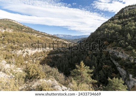 scenic mountainous landscape, densely covered with green trees under a blue sky with wispy clouds. It's a serene, undisturbed natural scene