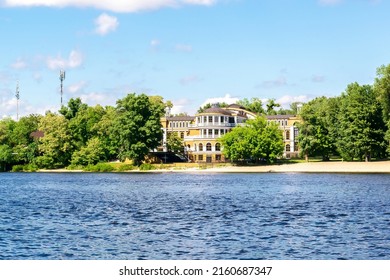 Scenic Nature Travel Cityscape Of River With Blue Water, Big Luxury Gorgeous House Building Architecture On Bay Coast Bank With Trees At Sunny Summer Day. View From Inside River.