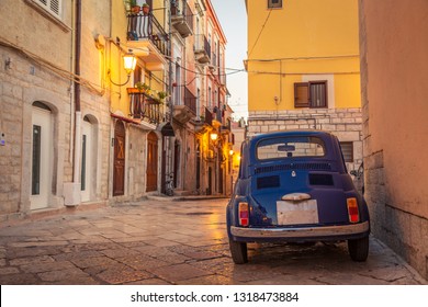 Scenic oldtown street and small retro blue car in Barletta city, Italy