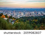 Scenic overlook from Pittock Mansion in Fall of Portland downtown with Mt Hood drenched in the orange light of the setting sun and waxing gibbous moon on the side.