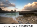 Scenic Pacitan beach, East Java. Green tidal flat and waves below massive limestone cliffs. Tropical coastline landscape, Indonesia.