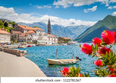 Scenic panorama view of the historic town of Perast at famous Bay of Kotor with blooming flowers on a beautiful sunny day with blue sky and clouds in summer, Montenegro, southern Europe