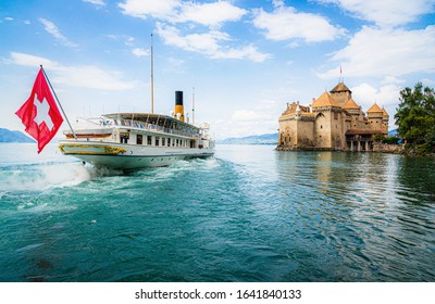 Scenic panoramic view of traditional paddle steamer excursion ship with historic Chateau de Chillon at famous Lake Geneva on a sunny day with blue sky and clouds in summer, Canton of Vaud, Switzerland