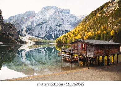 Scenic panoramic view of traditional wooden boathouse on the shores of famous Lago di Braies with Dolomited mountain peaks and beautiful reflections on a sunny day in fall, South Tyrol, Italy - Powered by Shutterstock