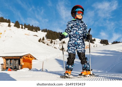 Scenic portrait view kid beginner skier close-up downhill start line rows freshly prepared groomed ski slope piste bright warm morning sunrise sky background.  mountain landscape winter resort