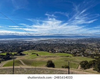 Scenic road by grassy hill near mountain with city view below - Powered by Shutterstock