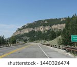 Scenic road winding around tall rocky granite cliffs approaching Ten Sleep, a town in the basin of Bighorn Mountains in Wyoming.