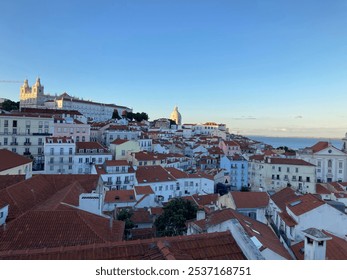 A scenic rooftop view over the historic district in Lisbon, Portugal, with colorful buildings and red-tiled roofs stretching toward the sea. Ideal for travel, architecture, and European culture themes - Powered by Shutterstock