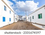 scenic row of white panited houses with sandy road in Famara, Lanzarote