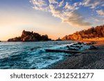scenic sea shore view of island in ocean with waves and amazing cloudy sunset or sunrise on backgeound, vacation landscape of rocky beautiful isle