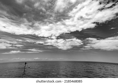 Scenic Seascape Of Calm Sea And Sky With Clouds. Man Floating On Sup Board. Black And White.