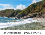 Scenic seascape of Steklyannaya Bay with waves, crashing on the beach with glass and rocks on the sunny summer day in Vladivostok