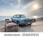 Scenic shot of a classic car parked on the beach with blue sky