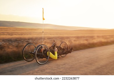 Scenic Shot of a Young Man Athlete with disability Riding a Handcycle. Adaptive Exercise Outdoors at Sunset . High quality photography. - Powered by Shutterstock