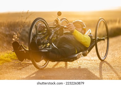 Scenic Shot of a Young Man Athlete with disability Riding a Handcycle. Adaptive Exercise Outdoors at Sunset . High quality photography. - Powered by Shutterstock