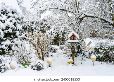 scenic snowy garden with a little birdhouse in traditional style on a stick - Powered by Shutterstock