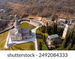 Scenic spring aerial view of monastic complex of Bodbe nunnery on hillside among tall Cypress trees with Church of St. Nino on sunny day, Sighnaghi, Georgia