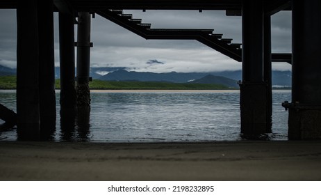 Scenic Stormy Cloudy Tropical Far North Queensland Landscape Looking From Under The Wharf In Port Douglas Towards Mangroves And Rain With Sand