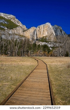 Scenic stroll along Yosemite pathway, capturing the mesmerizing waterfall and lush nature surrounding it.