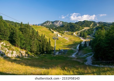 Scenic summer view of Vogel ski resort area near famous Bohinj lake, Triglav national park, Julian Alps, Slovenia. Empty cableway, white roads, green trees and mountains illuminated with sunlight