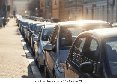 Scenic sunlit view row parked cars on busy city street in european city. Sidewalk parallel side parking full of vehicles traffic jam in downtown on warm sunset evening or sunrise morning - Powered by Shutterstock
