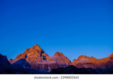 Scenic sunrise view of  mountain summit Monte Viso (Monviso) in the Cottian Alps, Piemonte, Italy, Europe. The rock walls of the Stone king are shining in warm red orange colors. Majestic landscape