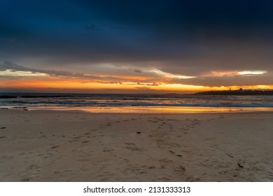 Scenic sunset on the ocean sandy beach with town silhouette on the horizon. Beautiful view landscape travel background. foorptints on sand. Australia - Powered by Shutterstock