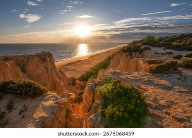 Scenic sunset over cliffs, pine forest, and golden beach in Mazagon, Huelva, Spain. Tranquil seascape ideal for travel, nature, and landscape concepts.