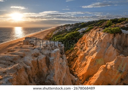 Scenic sunset over cliffs, pine forest, and golden beach in Mazagon, Huelva, Spain. Tranquil seascape ideal for travel, nature, and landscape concepts.