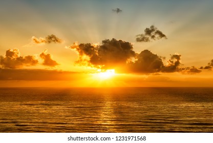 scenic sunset over pacific ocean with setting sun rays coming through dramatic clouds on orange blue sky reflecting on water panoramic aerial nature dusk atmosphere evening landscape background - Powered by Shutterstock