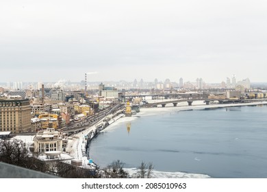 Scenic top panoramic view of Kyiv city Podol old center over ice covered Dnepr river Rybalskiy island panoramic landscape white winter snowfall. Cold season Ukrainian capital Kiev blizzard panorama - Shutterstock ID 2085010963
