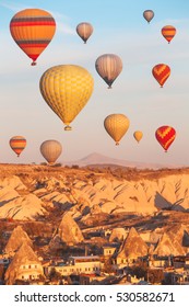 Scenic vibrant view of balloons flight in Cappadocia valley in sunrise rays.