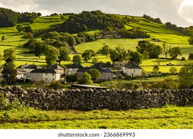 The Scenic view of a beautiful Bradford Dale English village nestling in a valley in the Peak District in Derbyshire, nestling in a valley, in the evening sun. - Shutterstock ID 2366869993