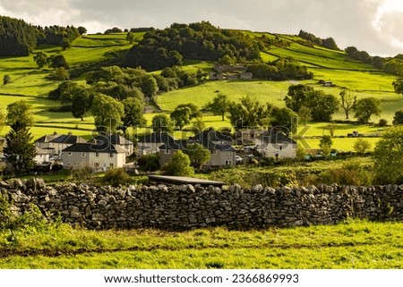 The Scenic view of a beautiful Bradford Dale English village nestling in a valley in the Peak District in Derbyshire, nestling in a valley, in the evening sun.