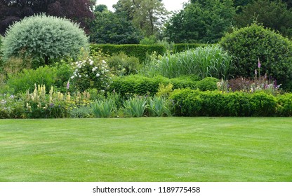 Panoramasicht auf einen schönen Landschaftsgarten im englischen Stil mit grünem Rasen und buntem BlumendBett