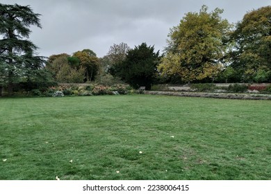 Scenic view of a beautiful English style garden with a large open green grass lawn and leafy trees
