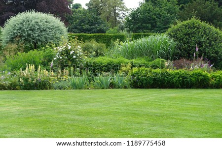 Scenic View of a Beautiful English Style Landscape Garden with a Green Mowed Lawn and Colourful Flower Bed