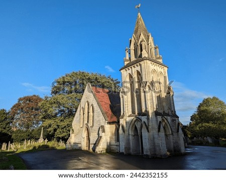 Scenic view of a beautiful old church building and graveyard in a green leafy forest with a clear blue sky above