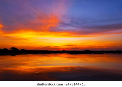 Scenic view of beautiful sunrise or dawn above the pond or lake at spring or early summer morning with cloudy sky background, clouds over water and reed grass with dew at foreground. Water reflection. - Powered by Shutterstock